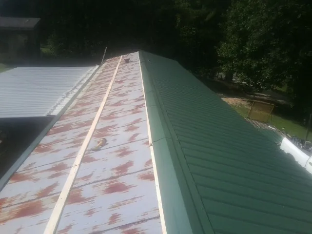 Old rusted panels beside newly installed green metal roofing — Wind Damage Roof Repair by Roofing Brothers in Shafer