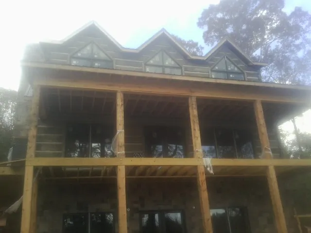 Dormers and porch framing on a large log home under construction — Roof Coating work by our crew in Shafer