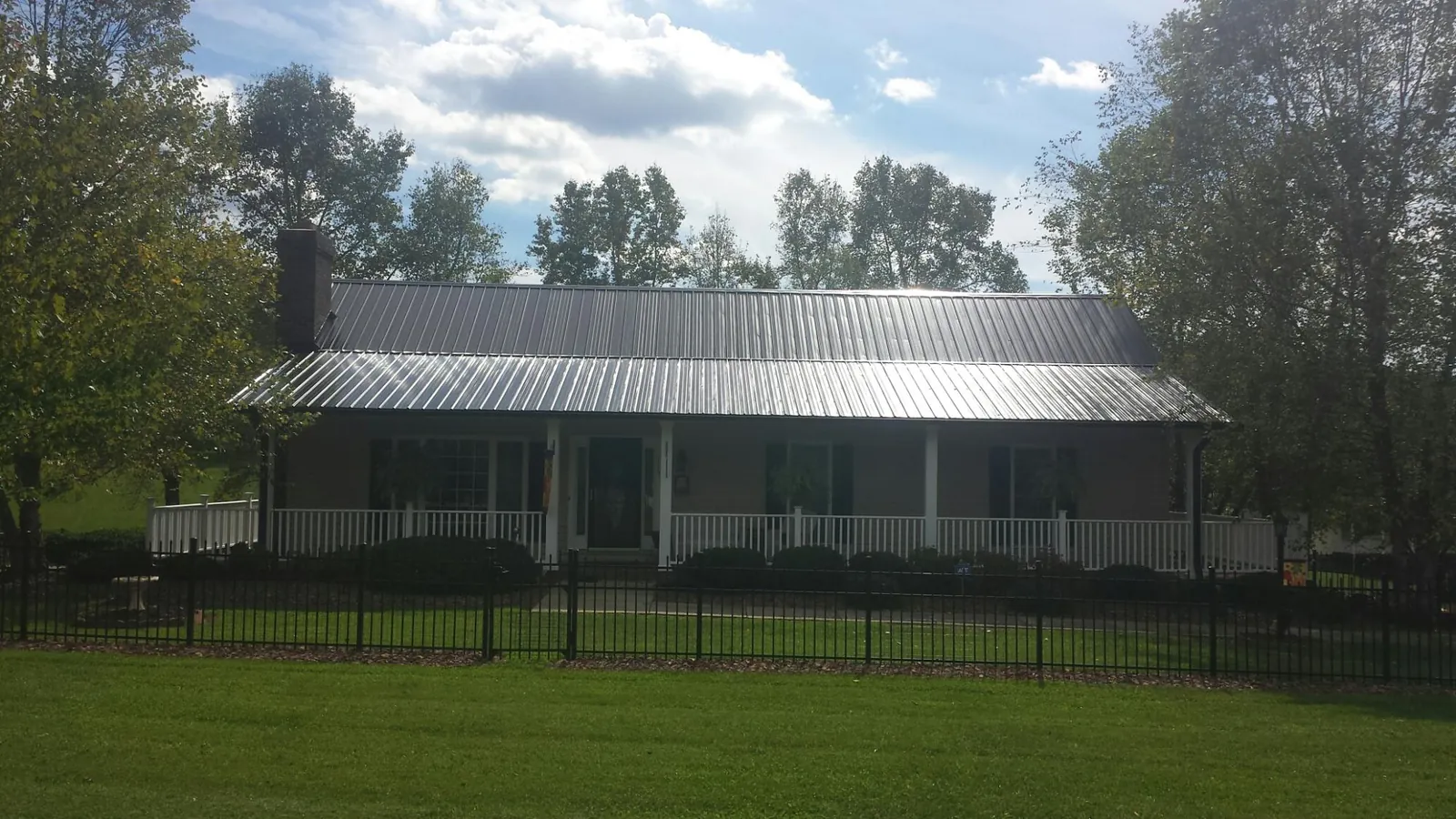 Gray metal roof on a brick ranch with a full width front porch — Gutter Guard Installation work by our crew in Shafer