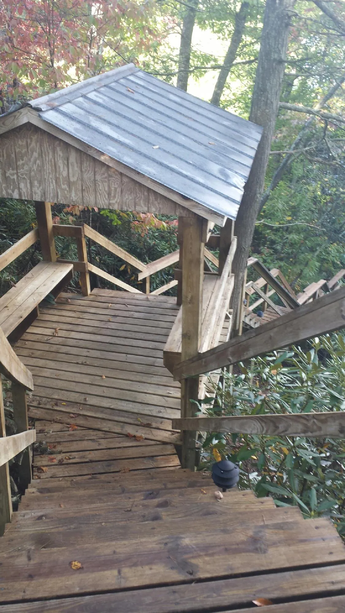 Metal roofed shelter over wooden steps on a wooded walkway — Skylight Repair & Installation work by our crew in Shafer