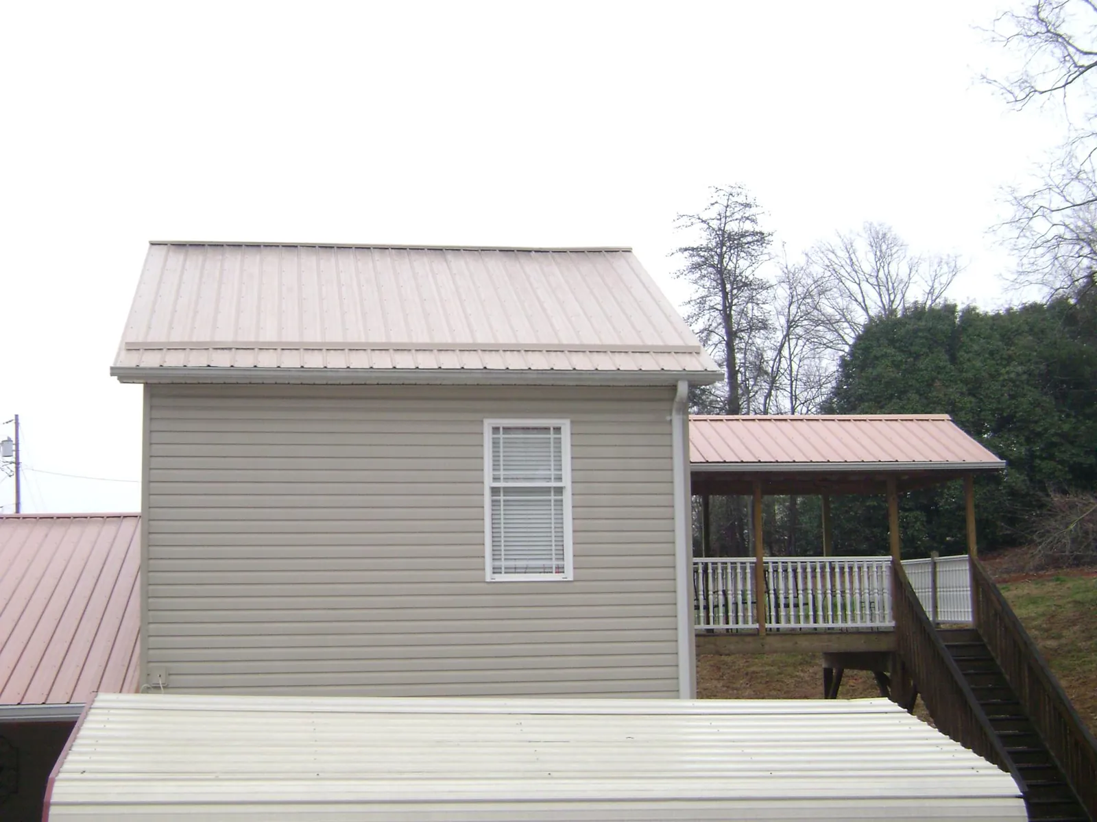 Tan metal roofs on a two story addition and attached porch, from a Roof Replacement job in Shafer