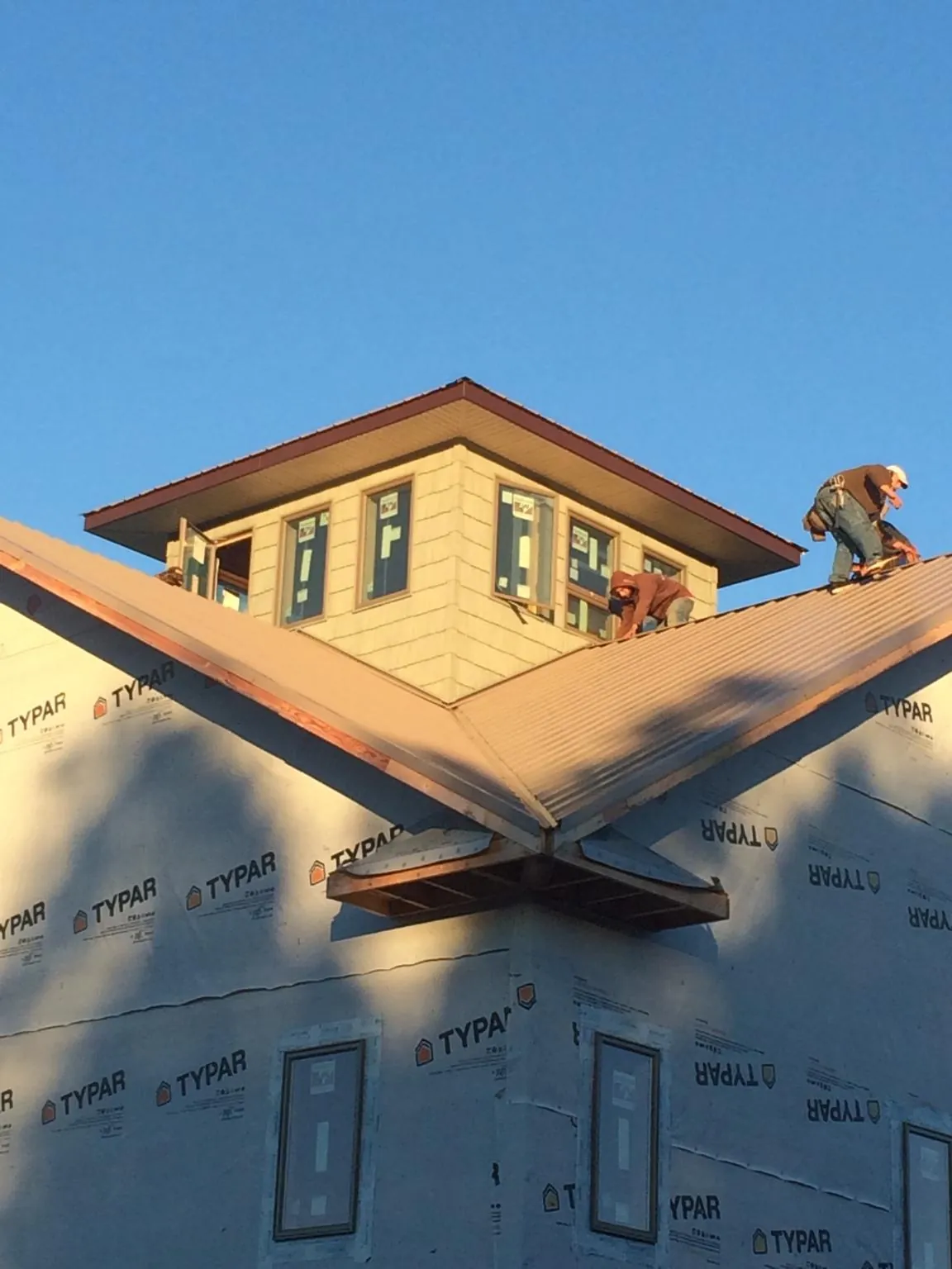 Roofers working around a rooftop cupola on a new metal roof at sunset — Roof Waterproofing in Shafer by Roofing Brothers